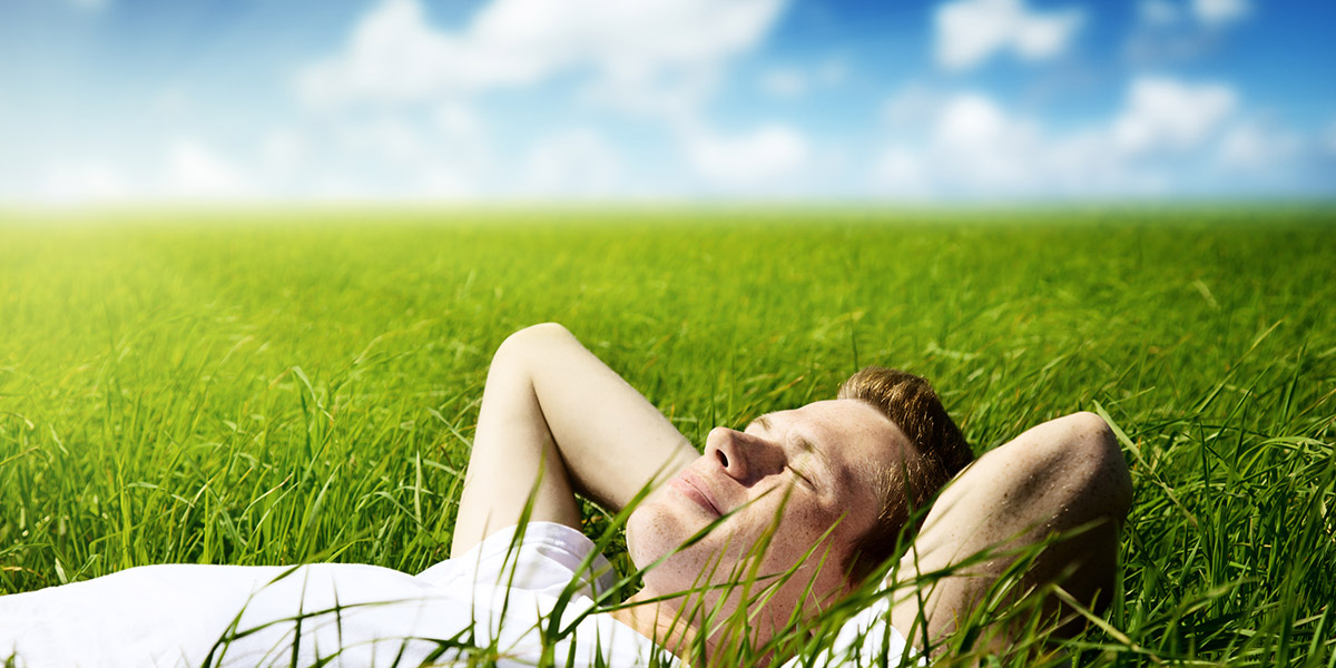 A man laying on his back in the grass with the sun hitting his face