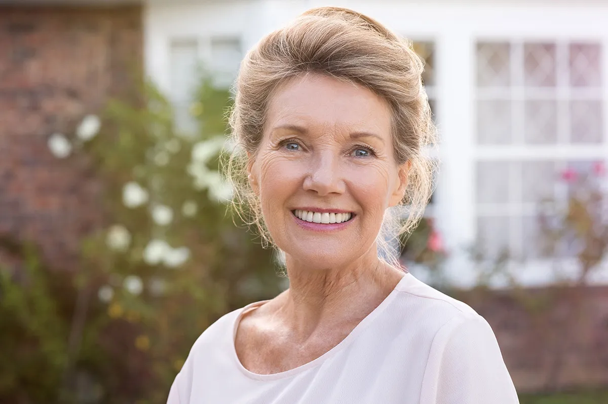 Image of a woman smiling at the camera after receiving snap-in dentures.