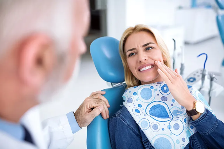 Image of a patient holding her mouth in pain from a toothache.