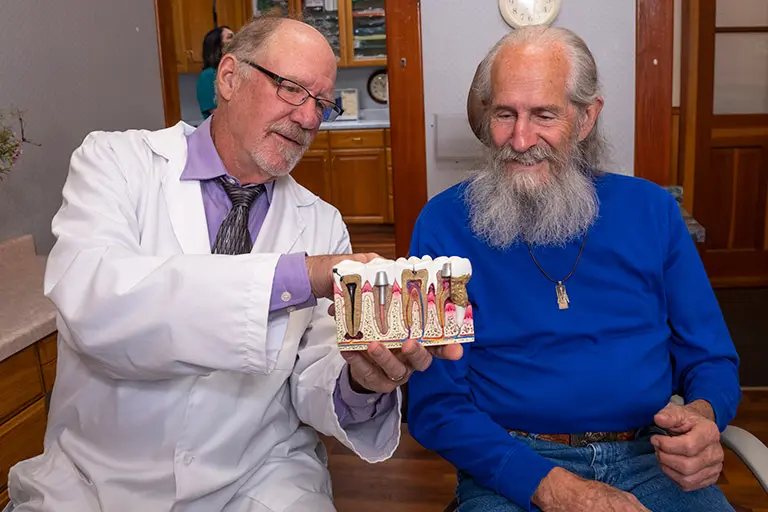 Dr. Herndon in a consultation with a patient, showing them a diagram of dental implants.