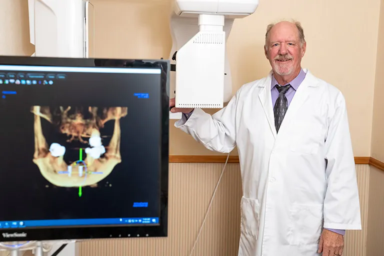 Image of Dr. Herndon standing next to a cone beam 3D Ct Scanner.